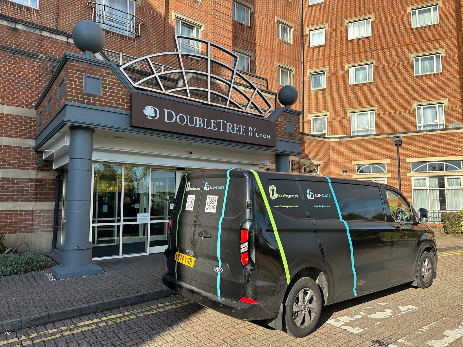 Door Engineers and Alu-Glaze branded service van at a DoubleTree by Hilton commercial site