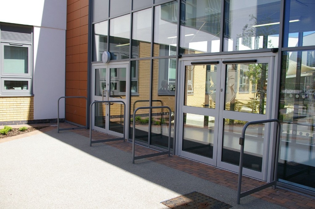 Aluminium-Framed Automatic Swing Double Doors With Overhead Operators And Safety Barriers At A Commercial Building Entrance