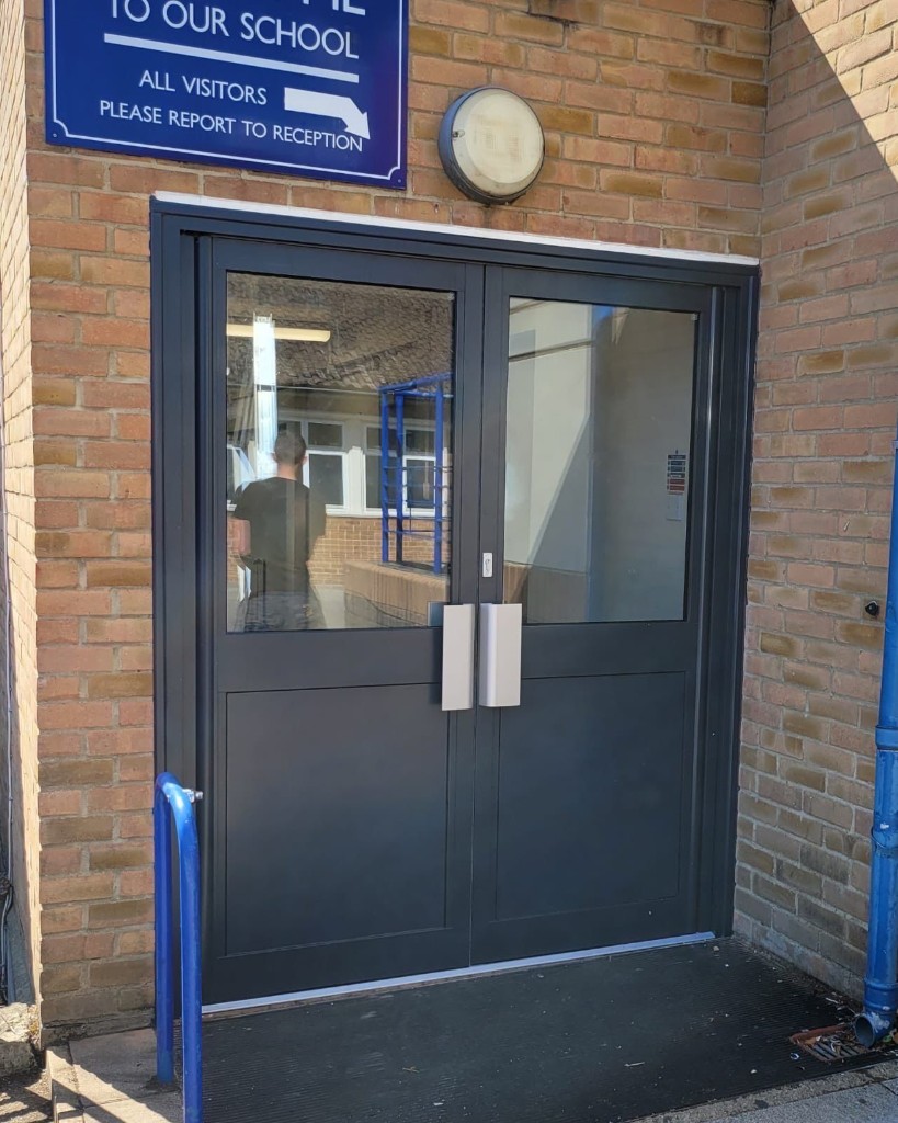 Anthracite Powder-Coated Double-Leaf Aluminium Entrance Doors With Glazed Panels And Pull Handles At A School Entrance