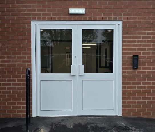 White powder-coated double-leaf aluminium entrance doors with glazed panels at Arc School in Arley, Nuneaton