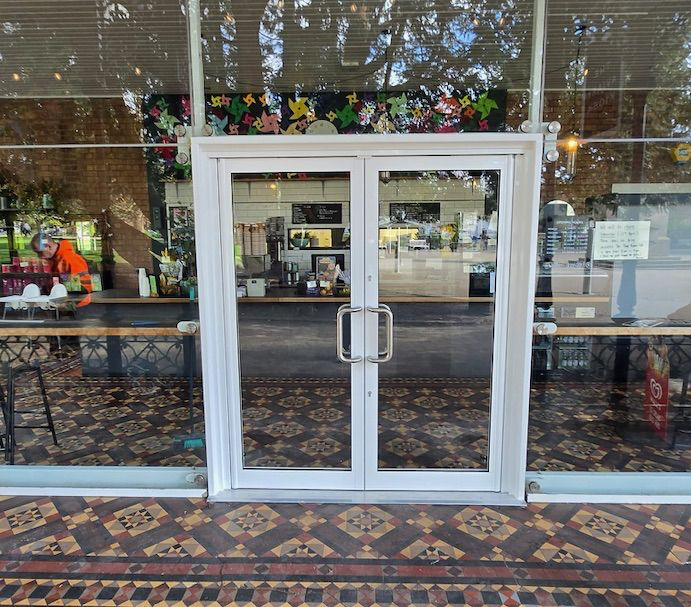 White powder-coated double-leaf aluminium entrance doors with pull handles at Avery Cafe in Leamington Spa