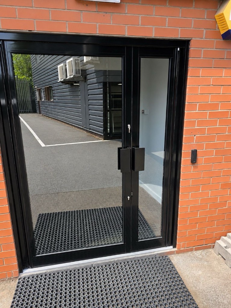 Black powder-coated unequal double-leaf aluminium entrance doors with pull handles at Voestalpine Metsec in Oldbury