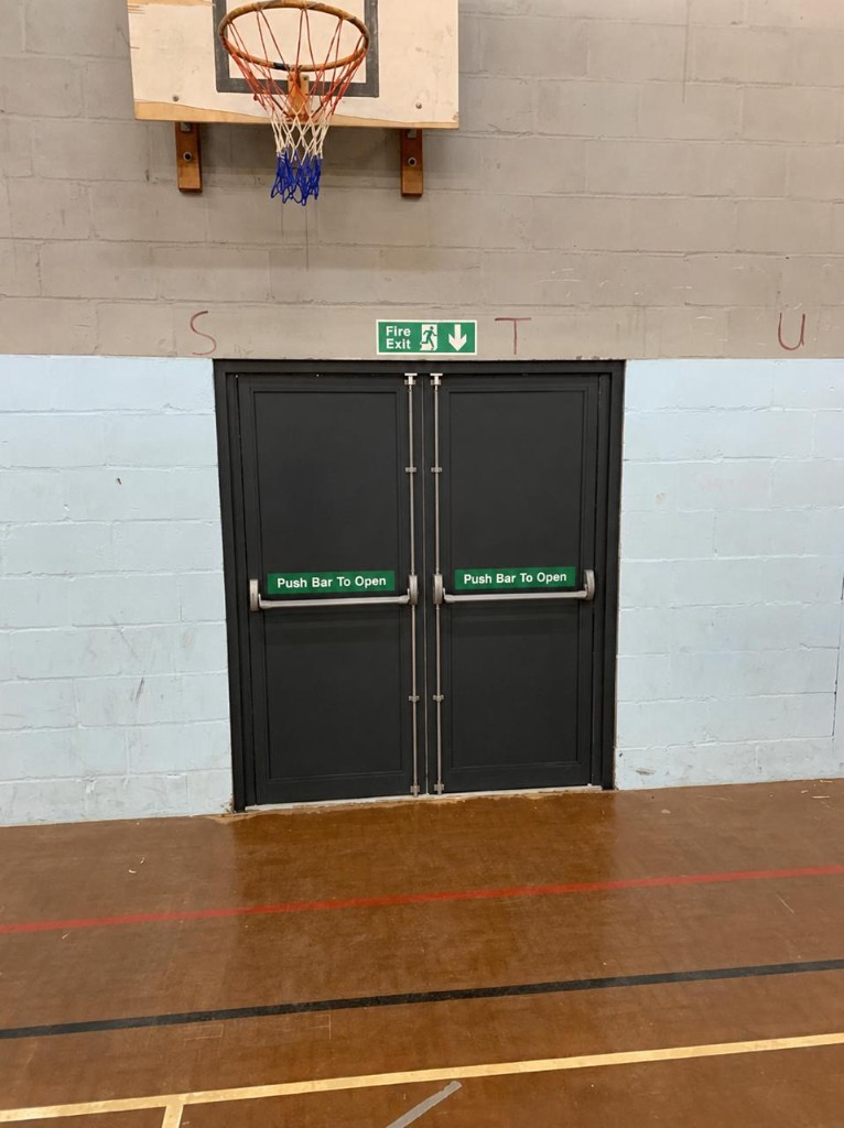 Anthracite aluminium double fire exit doors with Exidor surface-mounted panic bars & push bar to open signage at an education academy in Surrey