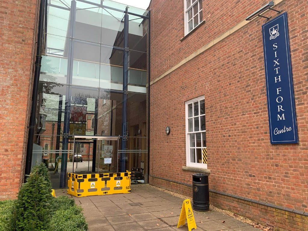Glass entrance doors with safety barrier during operational adjustment works at a sixth form centre