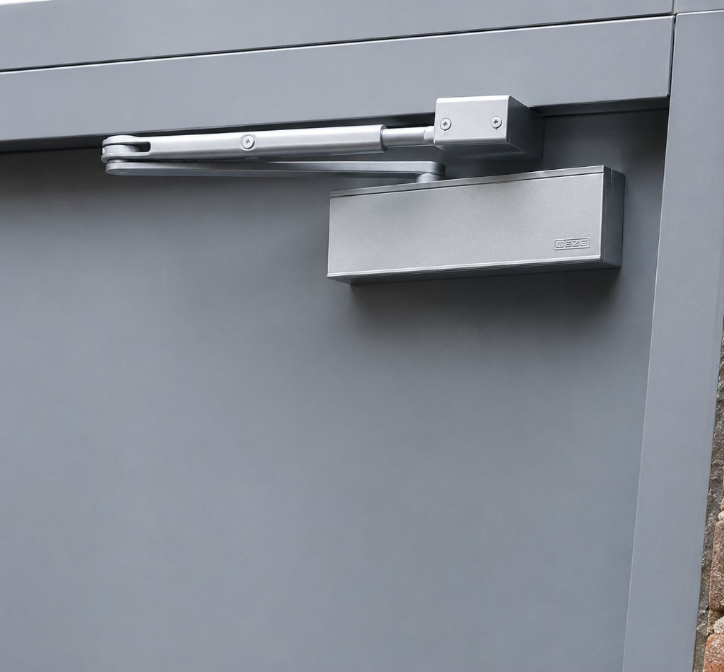 GEZE overhead door closer with slide arm system fitted to a grey aluminium commercial door