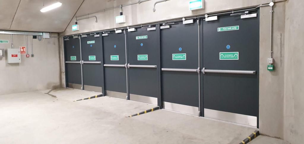 Steel Fire Exit Doors With Panic Bars And Emergency Exit Signage In A Commercial Plant Room