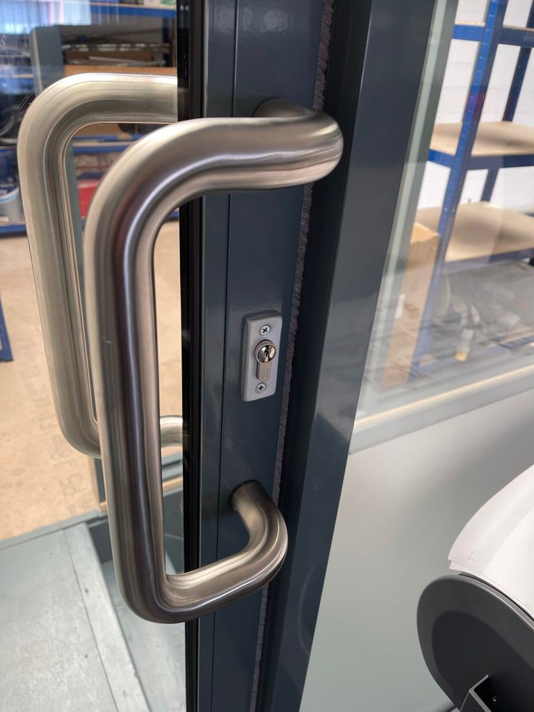 Commercial aluminium door with cylinder lock & curved pull handles during locking system inspection