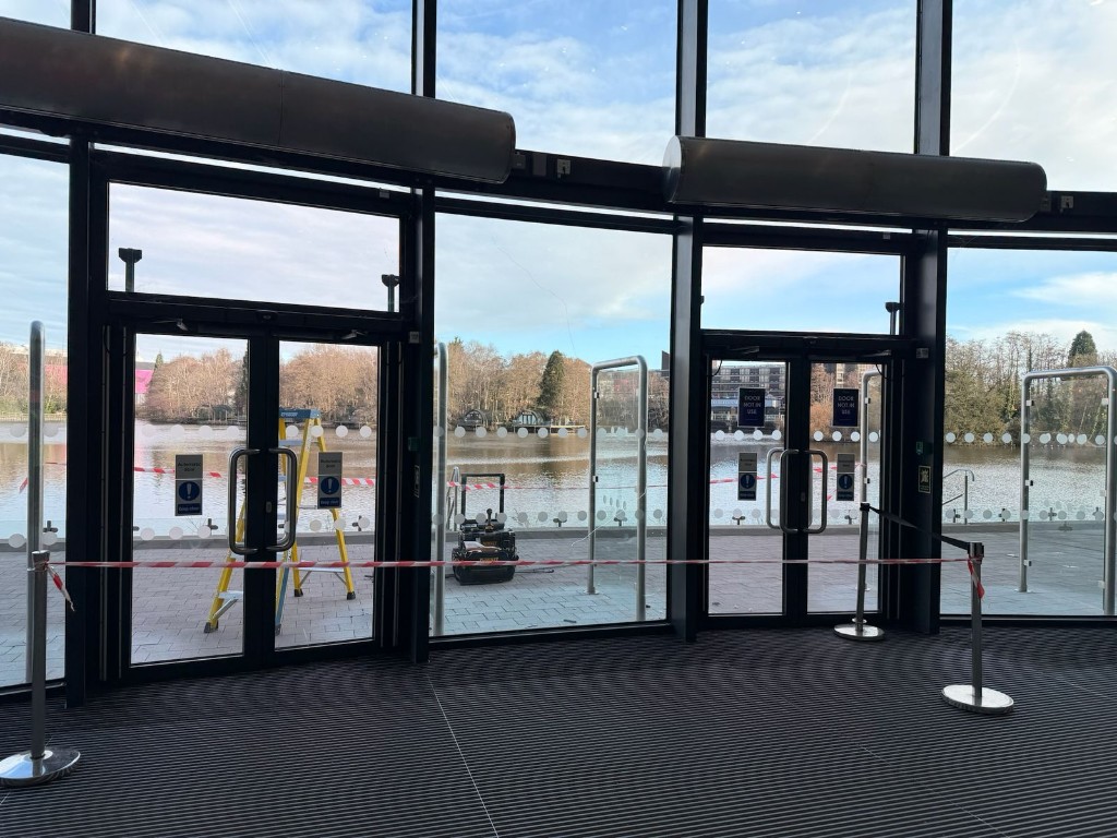 Automatic glass entrance doors cordoned off for performance verification & safety testing at a commercial building