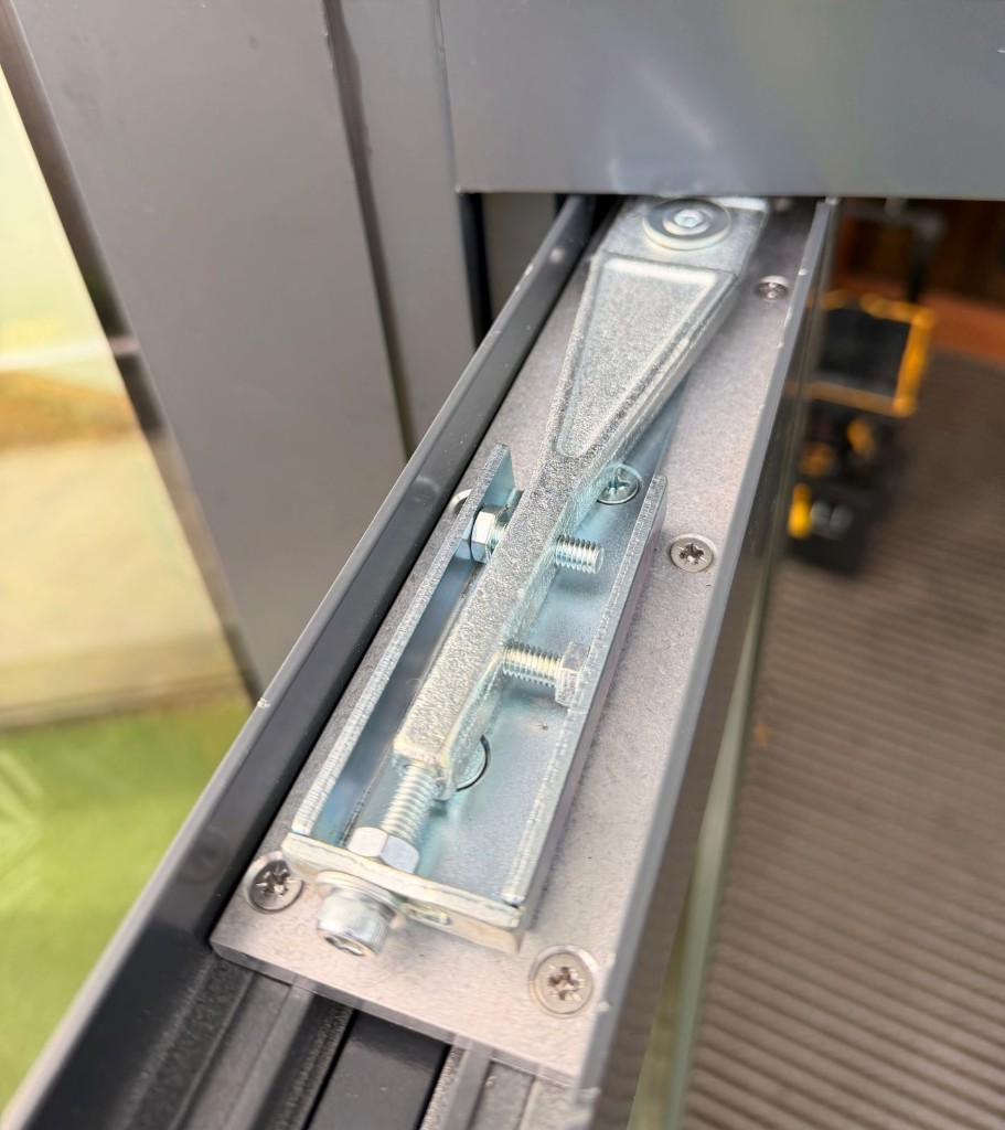Concealed transom closer mechanism & adjustment hardware inside an aluminium door head during inspection