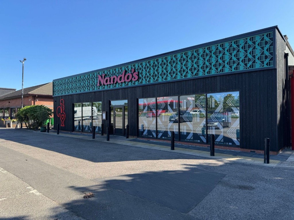 Nando's restaurant aluminium shopfront with black framed glazing, decorative frieze & illuminated branding in Nottingham