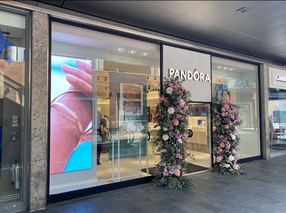 Pandora frameless glass shopfront with AP glass entrance doors, architectural patch fittings, gold branding & large-format glazing at Liverpool One