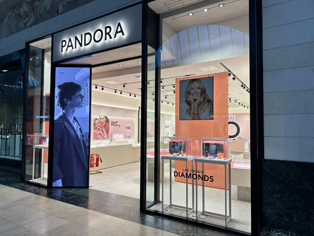 Pandora Retail Shopfront With Slim Black Aluminium Framing, Large-Format Glazing And Illuminated Signage In A Shopping Centre